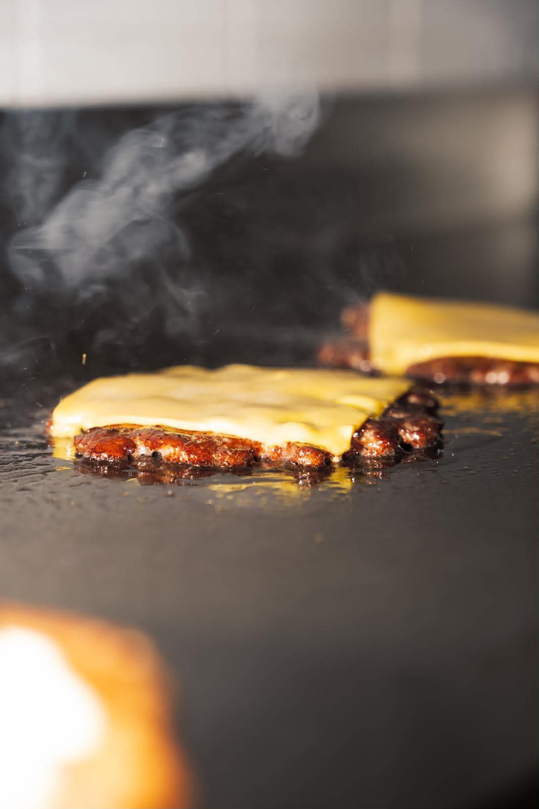 Hamburger di Fassona schiacciato sulla piastra rovente con cheddar che si scioglie