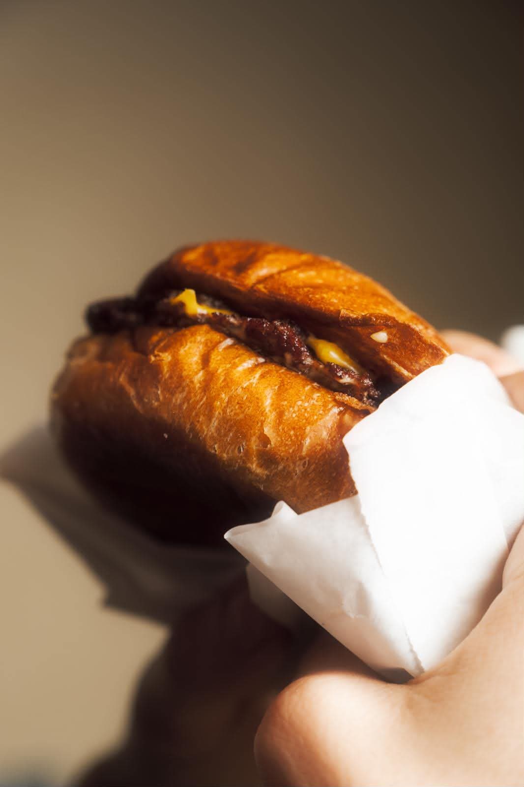 Hamburger in mano pronto per il morso, luce calda